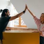 two people doing high five over a large cardboard box