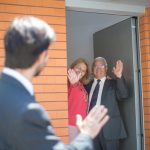 a man is saying goodbye to two other people in front of their house